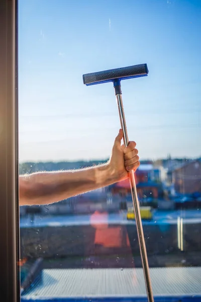 Window cleaning in high-rise buildings, houses with a brush. Window cleaning brush. Large window in a multi-storey building, cleaning service. Dust removal and glass washing.