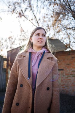 Kahverengi ceketli, pembe takım elbiseli ve pembe şapkalı şık bir kız modeli çok güzel gülümsüyor. Modern moda eğilimleri. Modaya uygun bir görüntü. Parlak duygular