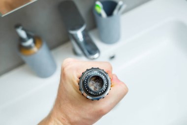 Mikserdeki su akışını ayarlamak için dönen hortum. Ellerini yıkamak için beyaz banyo lavabosu