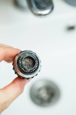 Mikserdeki su akışını ayarlamak için dönen hortum. Ellerini yıkamak için beyaz banyo lavabosu