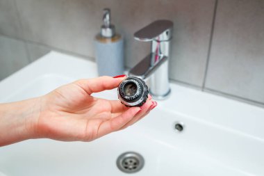Mikserdeki su akışını ayarlamak için dönen hortum. Ellerini yıkamak için beyaz banyo lavabosu