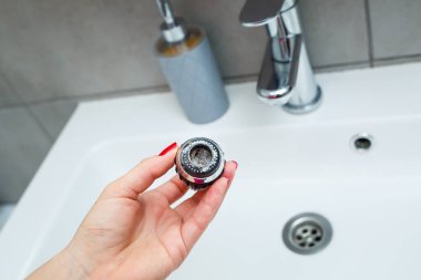 Mikserdeki su akışını ayarlamak için dönen hortum. Ellerini yıkamak için beyaz banyo lavabosu