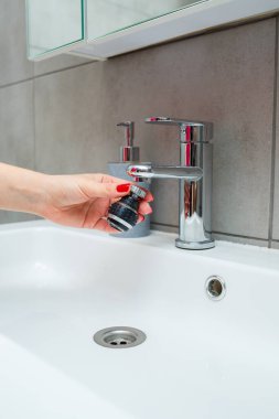 Mikserdeki su akışını ayarlamak için dönen hortum. Ellerini yıkamak için beyaz banyo lavabosu