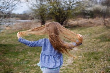 Paskalya yumurtası avında çiçek açan elma bahçesinde oynayan sevimli küçük kız koşuyor ve gülümsüyor. Bahar meyve bahçesinde kiraz çiçekli bir çocuk.