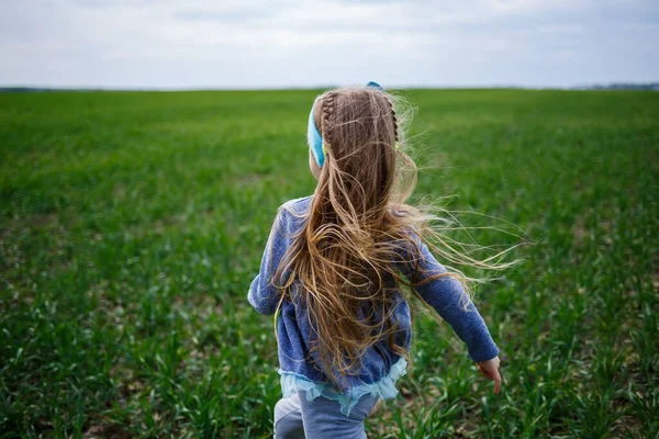 小女孩在田野里的青草上奔跑 春天里阳光明媚 孩子的微笑和欢乐 蓝天乌云密布 — 图库照片