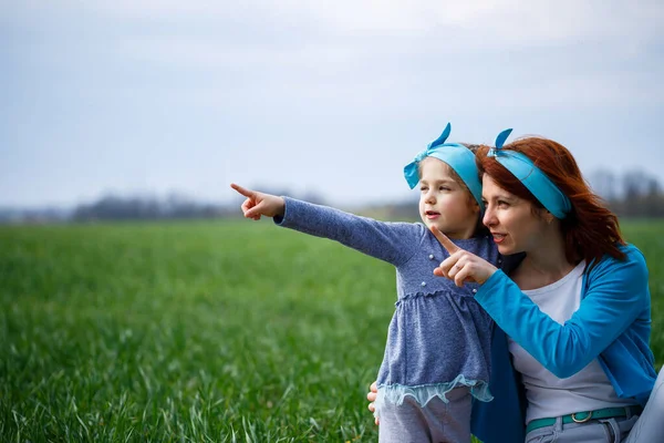 小女孩和妈妈坐在床罩上 青草在田野里 春天里阳光明媚 孩子的微笑和欢乐 蓝天乌云密布 — 图库照片