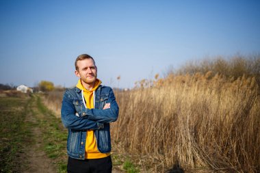 Gülümseyen adam ormanda esen rüzgardan zevk alıyor. Doğada yürürken mutlu bir adam, yeşil ağaçların arkasında boş bir alan. Hayat aşkı, neşe, temiz hava, yenileme konsepti