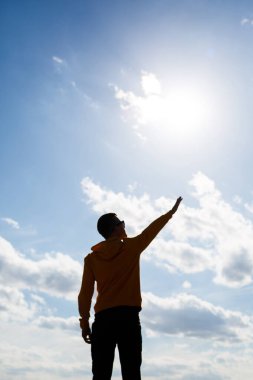 Adam, beyaz bulutlu mavi gökyüzünün arka planında serbest turist, güneşli bir gün, doğa ve insan özgürlüğü.