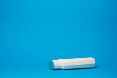 Kremalı beyaz şişe, saç şampuanı, duş jeli, izole edilmiş mavi arka plan, insan vücudu güzelliği