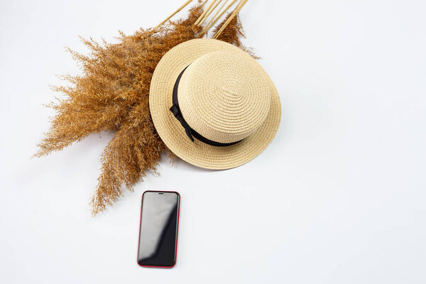 Mobile phone, hat, lifestyle, woman, relax, with dry grass, decor, flat lay, style on a white background. Travel, tourism concept. Beach accessories top view.