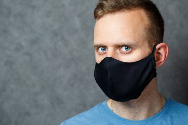 Siyah koruyucu maskeli genç adam virüslere karşı. COVID 19