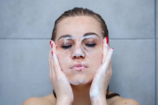 面部皮肤护理 女性在面部特写时使用面部清洁剂 女孩在皮肤上使用清洁化妆品 在浅色背景上洗脸 — 图库照片