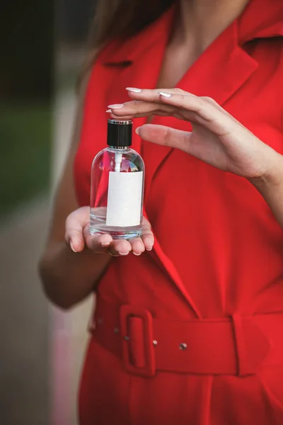 Perfume bottle of a female hand. Young stylish woman holding a bottle of perfume. Fashionable perfume in the hands of women. Girl spraying perfume. Beautiful female hands. Perfumes for women