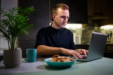 Bir serbest çalışan mutfakta çalışır ve dizüstü bilgisayar kullanır. Bilgisayarla çalışıp iyi haberler okuyan başarılı bir adam. Yakışıklı başarılı girişimci modern evinde oturur ve çalışır..