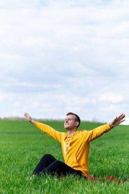 Yeşil çimlerde oturan genç bir adam geleceği düşünüyor. Yakışıklı bir adam güneşli bir yaz gününde parkta dinleniyor. Tatil kavramı