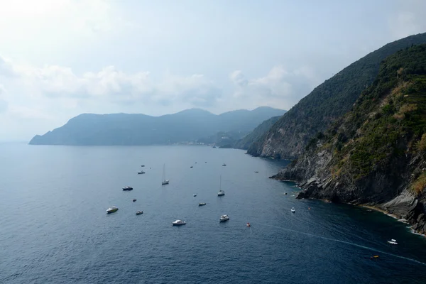 Boats in bay and high cliff in Vernazza, Italy — Stock fotografie