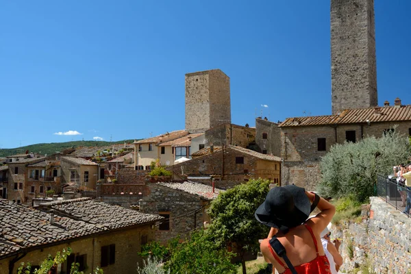 Femme au chapeau noir prenant des photos de la ville de San Gimignano . — Photo