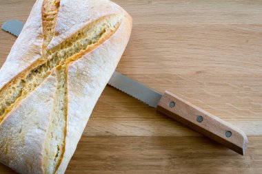 Ahşap meşe masa üstündeki ekmek ve bıçak somun.