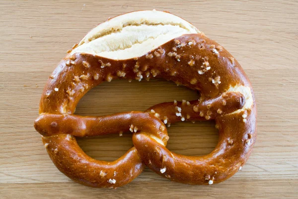 Salted pretzel on wooden oak table top. — Stock Photo, Image