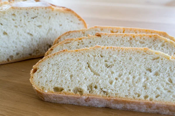 Fette e pagnotta di pane sul tavolo di legno . — Foto Stock