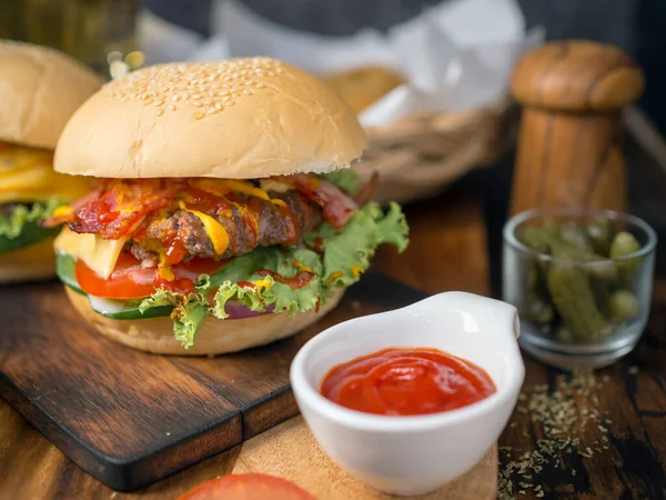 Homemade burgers with beer and cola made of bacon, pork, tomato, lettuce, onion, cheese and spices on wooden background
