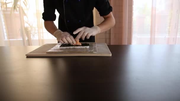 Sushi szef kuchni rozprzestrzenia mięso krabowe na liście nori. Sushi roll procesu decyzyjnego.Chefs ręce.Bamboo mat — Wideo stockowe