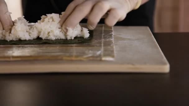 Крупный план суши мастер распространяет рис на nori.Sushi решений process.Chefs hands.Bamboo мат — стоковое видео