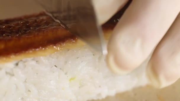 Kés közeli vágás sushi tekercs rizs és füstölt angolna egy késsel.Sushi készítési folyamat — Stock videók