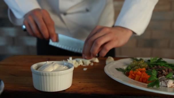Der Koch schneidet das gekochte Ei mit einem Messer in Scheiben. Kochen russischer Salat. — Stockvideo