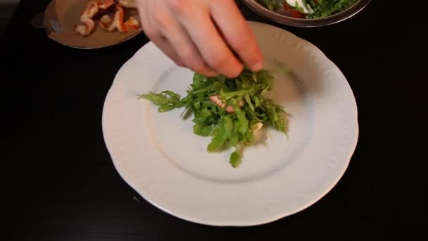 Kook zet op een bord arugula, aardbeien, kerstomaten, mozzarella kaas, gegrilde garnalen.Close-up. — Stockvideo