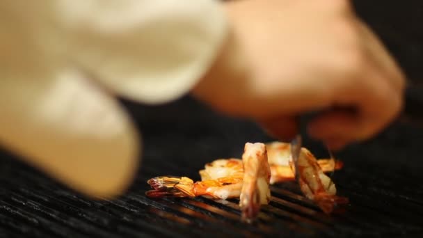 Gros plan de Cook retourne les crevettes fumées sur le gril .