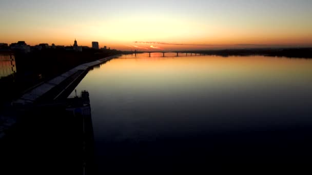 Oscura Vista aérea del puente a través de un amplio río al atardecer. La puesta de sol se refleja en el agua. . — Vídeos de Stock