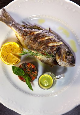 Gri ızgara Dorado, limon, biberiye, sebze ve yeşil sos ile servis edilir. Yukarıdan manzara