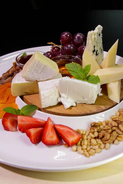 Camembert peyniri, parmesan peyniri, üzümlü mavi peynir, reçel, bal, çilek, kurutulmuş kayısı ve fındık. Peynir tabağı..