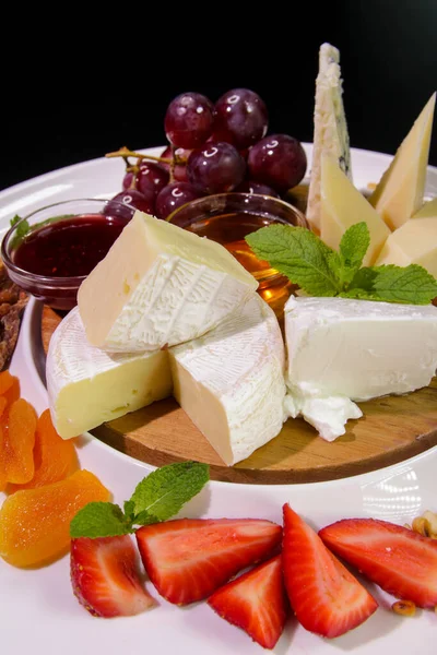 Camembert peyniri, parmesan peyniri, üzümlü mavi peynir, nane, reçel, incir, bal, çilek, beyaz tabakta kurutulmuş kayısı. Peynir tabağı..