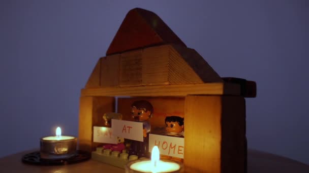 Les hommes Lego tenant des affiches RESTEZ À LA MAISON dans une maison de jouets en lambeaux . — Video