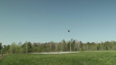 Bir helikopter ormanın ve tarlanın üzerinden uçuyor..