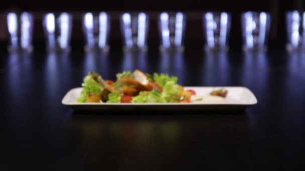 Bord met gerookte vis met groene saladebladeren en tomaten. — Stockvideo