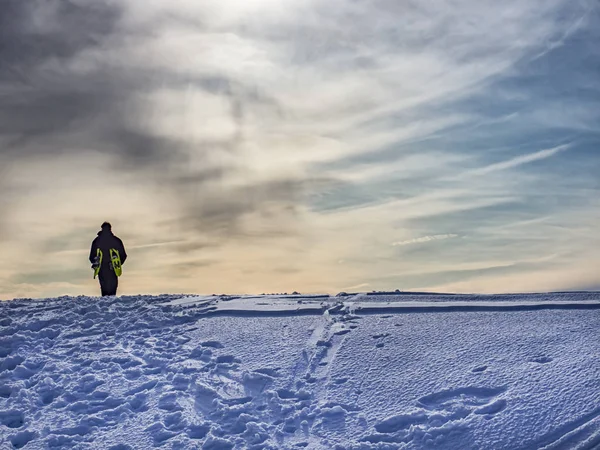 Hombre caminando en la nieve al atardecer —  Fotos de Stock