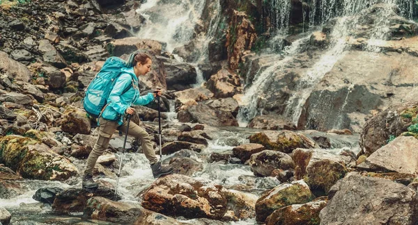 Backpacker Młoda Kobieta Przekraczania Góry Rzeka Kijki Trekkingowe Pobliżu Wodospadu — Zdjęcie stockowe
