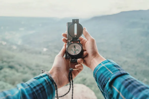 Traveler searching direction with a compass in the mountains. Point of view shot