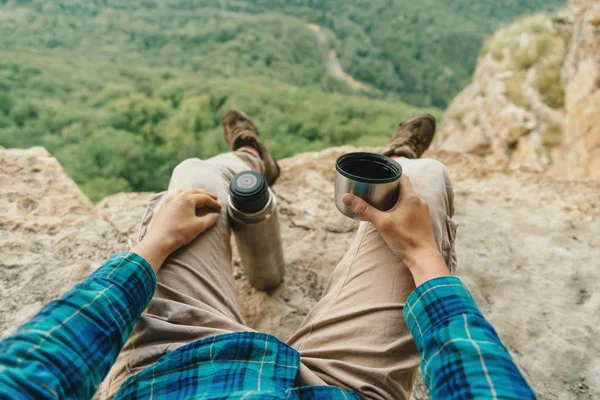 坐在悬崖上的旅行者 从山上的热水瓶里喝茶 — 图库照片
