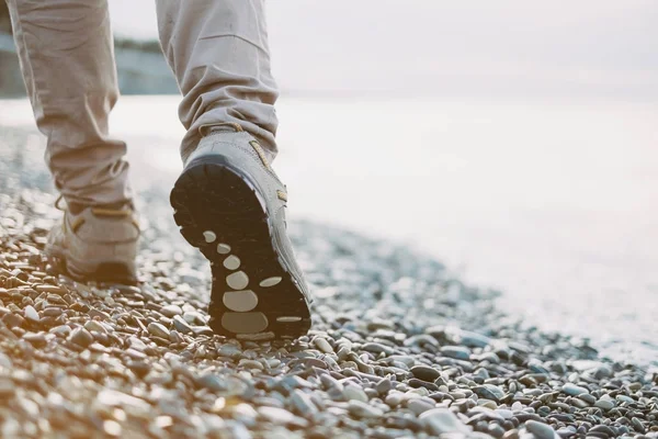 海のそばの小石の海岸の上を歩く女性の脚のビュー — ストック写真
