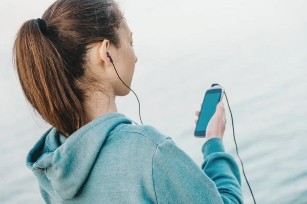 Fitness woman listening music on smartphone — Stock Photo, Image