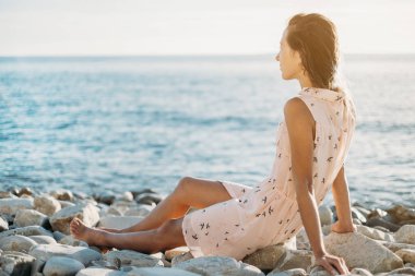 Çakıl plajı üzerinde oturan kız.