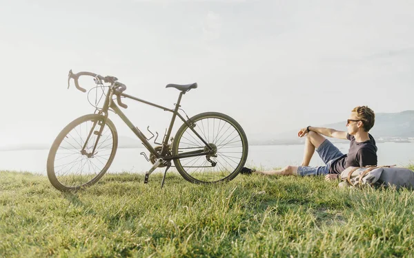 Cyclist rests on summer meadow. — Stock Photo, Image