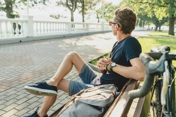 Guy ciclista descansa no banco de madeira . — Fotografia de Stock