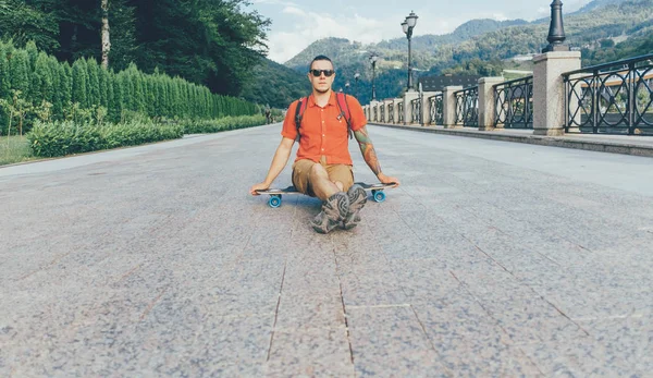 Guy sitting on longboard outdoor. — Stock Photo, Image