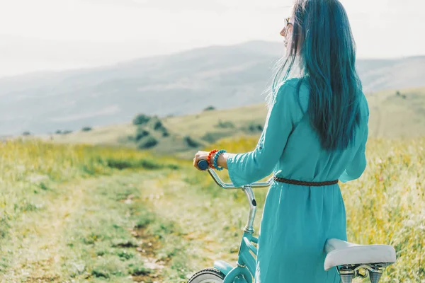 Молодая женщина стоит с велосипедом на открытом воздухе . — стоковое фото