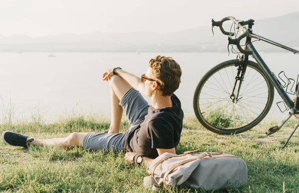 Ciclista uomo riposa sul prato estivo . — Foto Stock